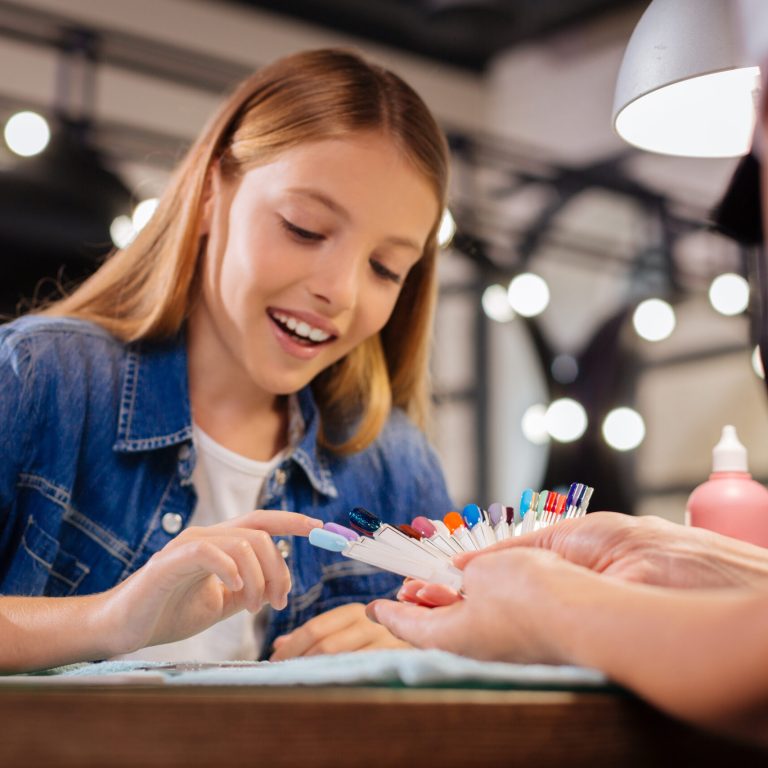 Love it. Gorgeous young girl sitting pointing at a nail polish color of her choice while smiling broadly
